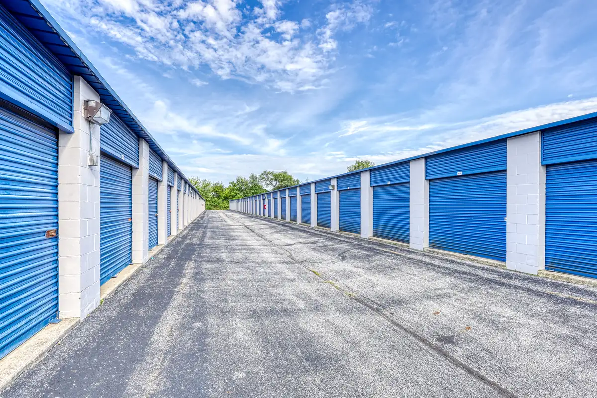 Wide perspective of a drive aisle lined with blue drive-up storage units under a clear sky in Indianapolis.