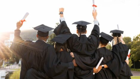 Behind a group of graduated students holding their diplomas.