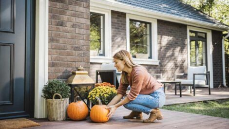 Woman setting up some fall decorations on the floor.