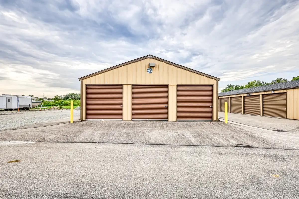 Front exterior of a tan storage building featuring three wide brown drive-up doors in Cicero, IN.