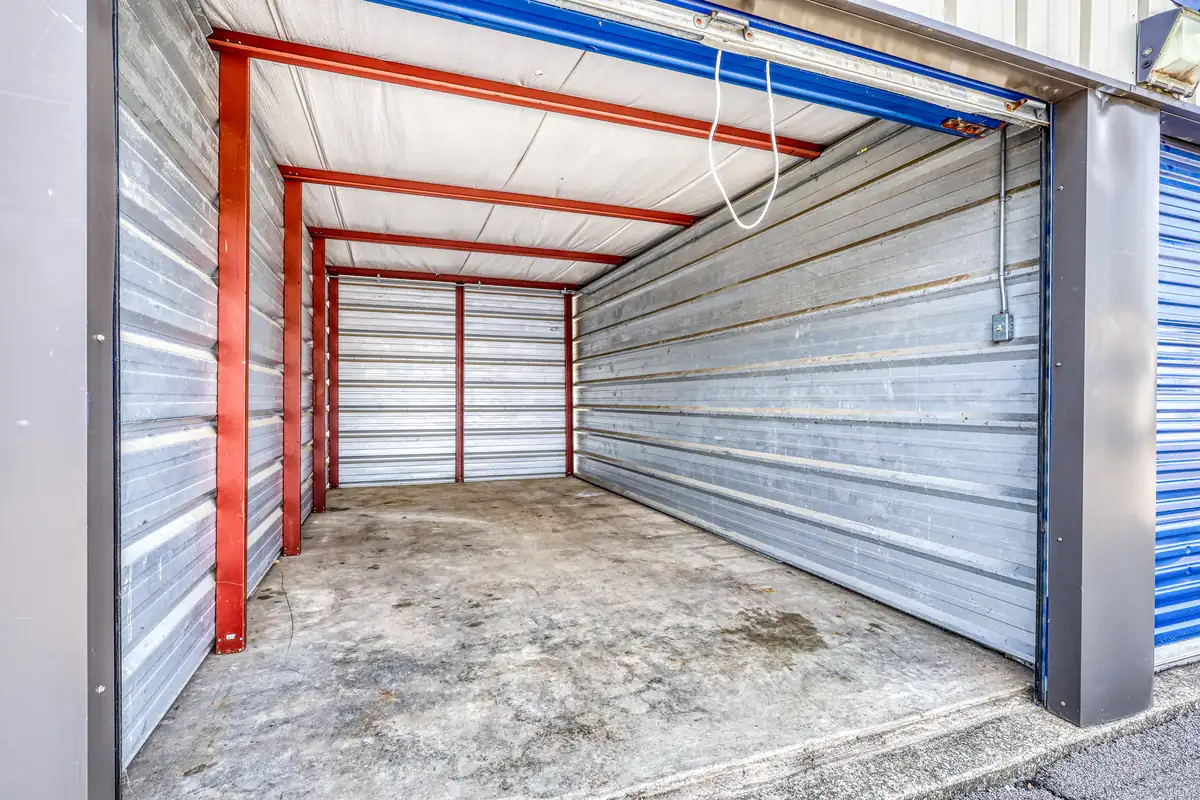 Interior view of a clean, empty drive-up storage unit showing metal walls and a concrete floor.