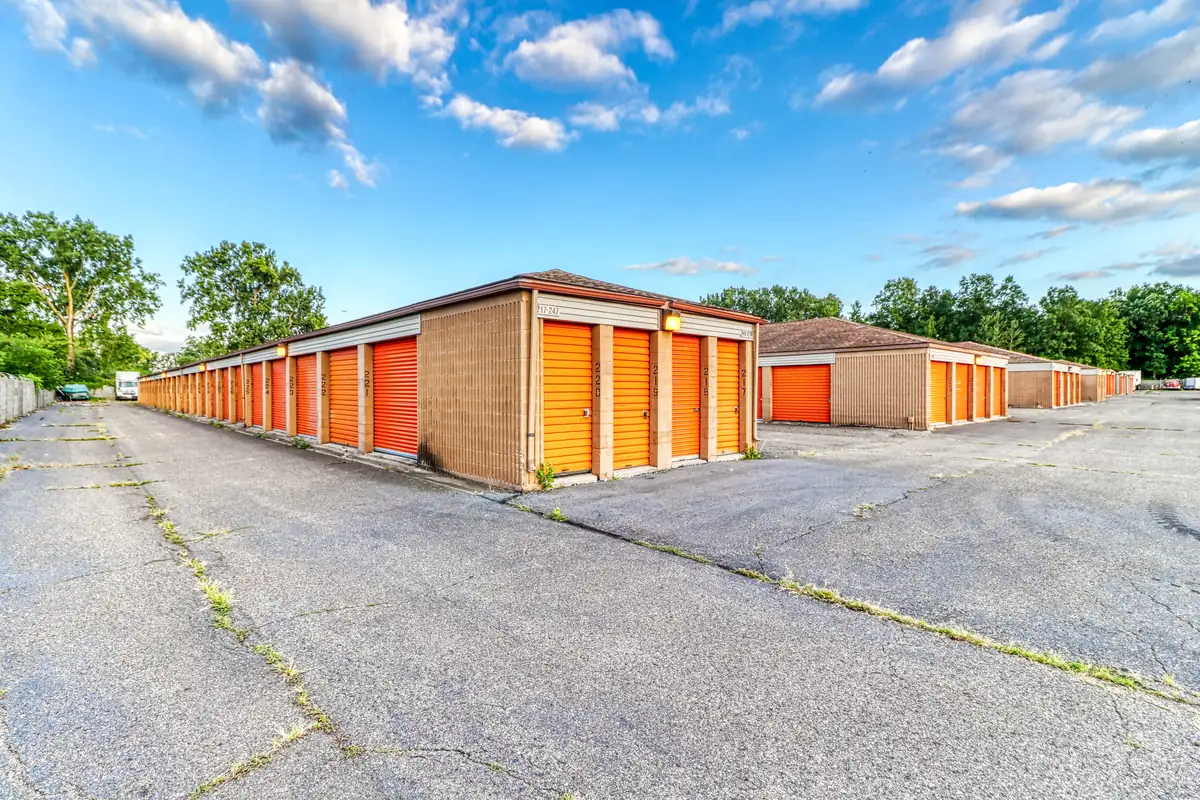 Row of orange roll-up doors on paved parking spaces at MyPlace Self-Storage on S Merriman Road in Westland, MI.