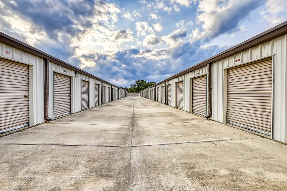 Wide paved drive aisle between rows of drive-up storage units in Pensacola, FL.